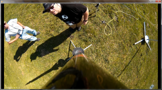 Frame from onboard camera looking down at two men, while the rocket is on the launch pad.