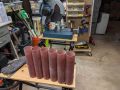 Six red fiberglass tubes, 2.1 inches diameter and 10 inches long, with a chop saw in the background.