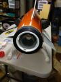 A photo of the nozzle end of an orange high-power rocket lying horizontally on a rack in the workshop.