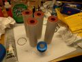 A photo of four 54mm motor grains, unassembled. The propellant is bright red.